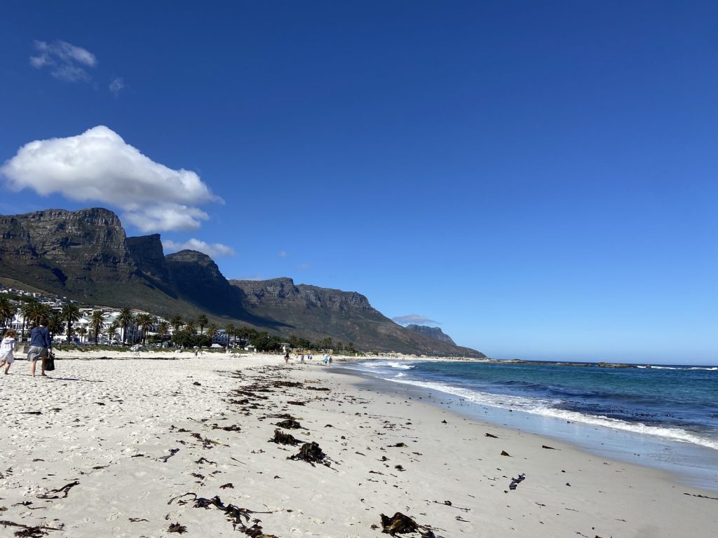 Camps Bay beach in Cape Town with the Twelve Apostles mountain range and a clear blue sky
