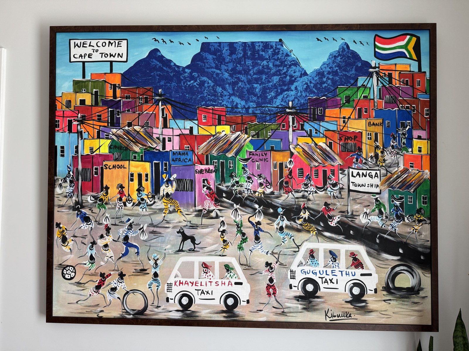 Welcome to Cape Town painting by Kibuuka — a vibrant township street scene with Table Mountain, bought from the artist in Cape Town